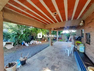 Vista de um pátio coberto com teto de madeira e piso de cerâmica.