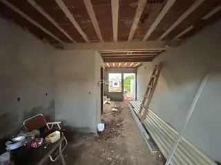 Interior de uma sala em construção com vigas de madeira expostas.