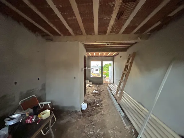 Interior de uma sala em construção com vigas de madeira expostas.