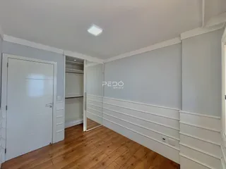 Interior de uma sala com piso de madeira e paredes brancas.