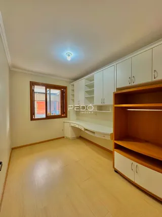Ambiente interno com piso de madeira clara e armários brancos em um imóvel.