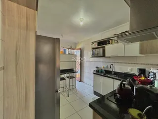 Cozinha moderna com armários brancos e piso claro.