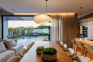 Vista de uma sala de jantar com acesso a uma área de piscina externa.