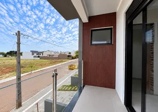 Vista da varanda mostrando uma rua e casas no horizonte sob um céu azul.