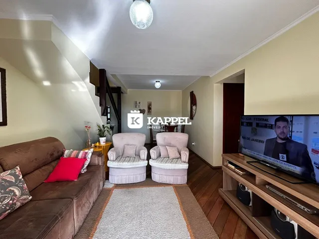 Sala de estar com sofá marrom e duas poltronas claras.