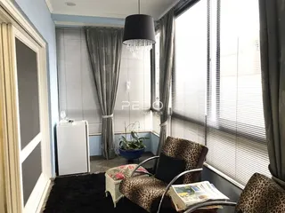 Sala de estar com grandes janelas e cortinas na residência.