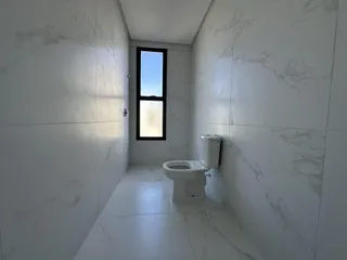 Foto de um corredor com revestimento de mármore branco e um vaso sanitário.