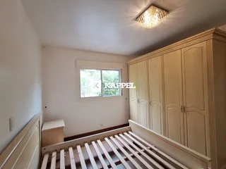 Quarto com cabeceira de madeira e armários embutidos em um ambiente claro.