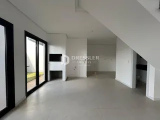 Interior de uma sala de estar moderna com piso de concreto e grandes portas de vidro.