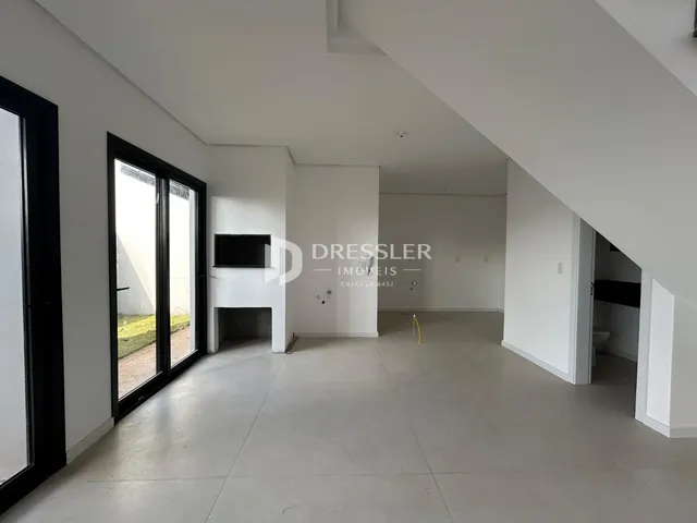 Interior de uma sala de estar moderna com piso de concreto e grandes portas de vidro.