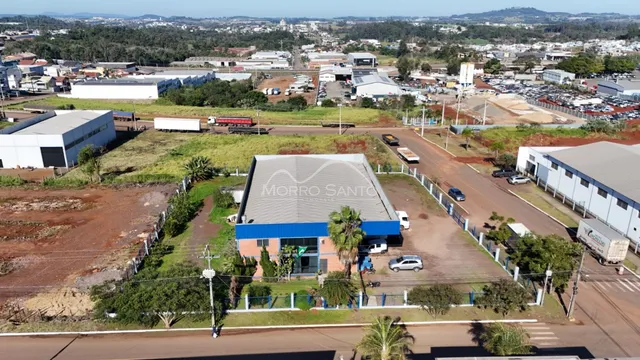 Vista externa de um terreno com um edifício industrial e área verde.