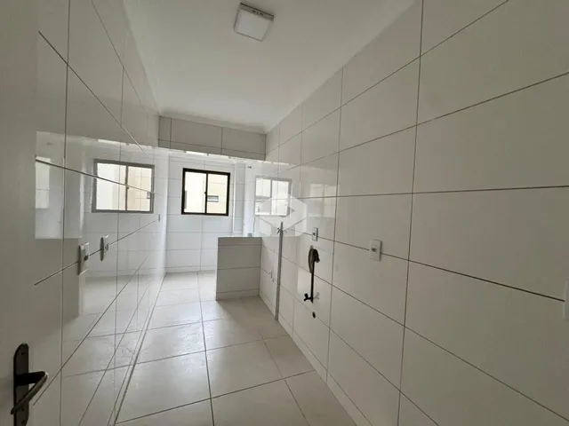 Corredor interno com paredes e piso brancos de cerâmica.