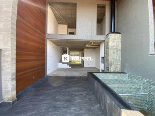 Vista de uma área externa com piso escuro e revestimento de madeira em um imóvel.