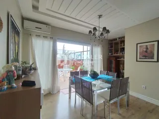 Sala de estar com piso de madeira e grandes janelas em um imóvel no Brasil.