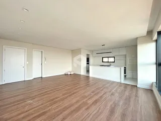 Ambiente interno de uma sala ampla com piso de madeira clara.