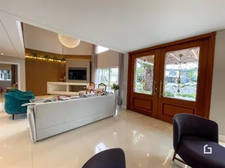 Sala de estar ampla com piso de cerâmica clara e portas de madeira.