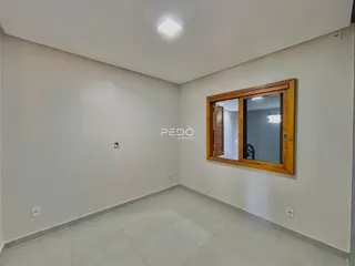 Interior de um cômodo com piso de cerâmica e janela de madeira.