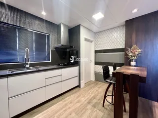 Vista de uma cozinha com armários brancos e piso de madeira clara.