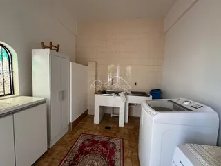 Foto de uma cozinha com bancada branca e máquina de lavar roupa.