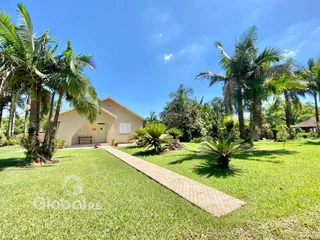 Fachada de uma casa em Lajeado, Brasil, com jardim verde e palmeiras.