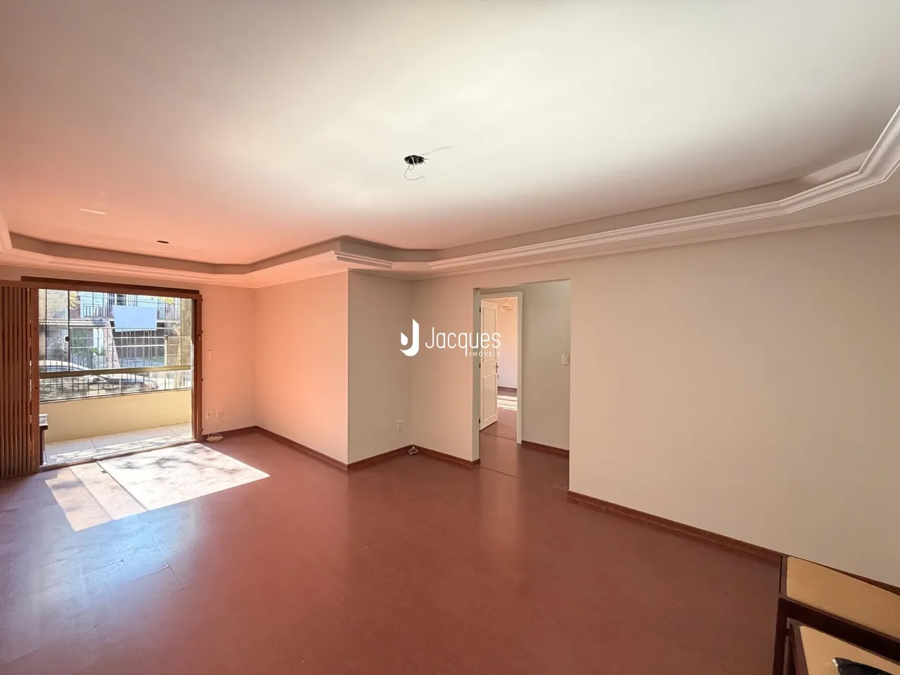 Sala de estar com piso de madeira e porta de entrada.