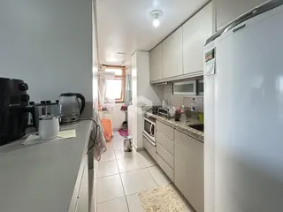 Uma vista da cozinha com armários brancos e piso de cerâmica.