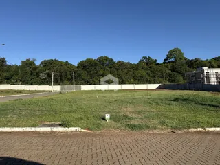 Vista externa de um terreno com cerca e vegetação ao fundo.