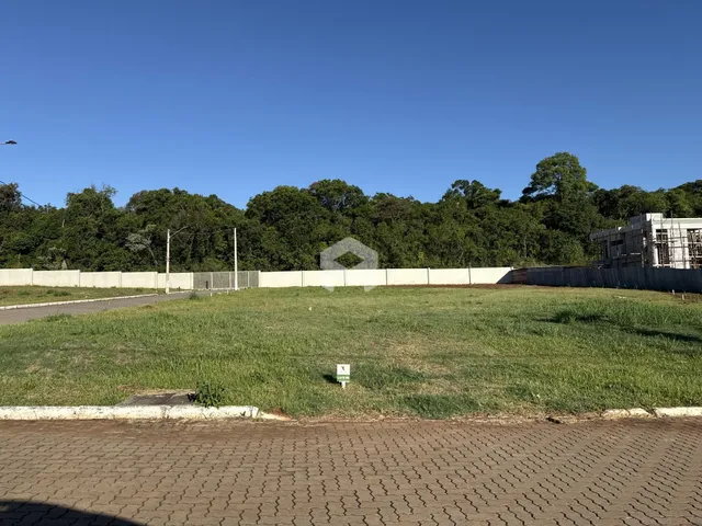 Vista externa de um terreno com cerca e vegetação ao fundo.
