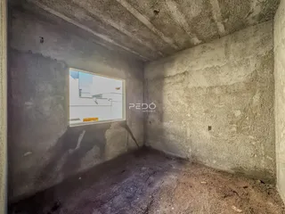 Ambiente interno de uma sala com paredes de concreto cru.