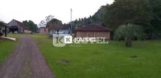 Vista externa do terreno com gramado e vegetação.