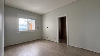 Uma sala de estar com piso de madeira e uma janela mostrando a paisagem externa.