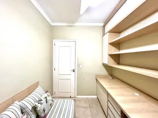 Quarto com cabeceira de madeira e estante em um apartamento.