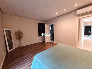 Quarto com piso de madeira e cabeceira de cama.