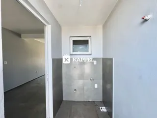 Hall de entrada interno com paredes cinzas e uma abertura para outro corredor.