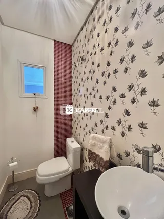 Banheiro com revestimento de azulejos vermelhos e papel de parede floral.