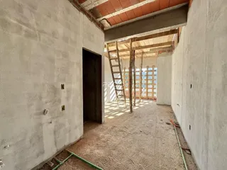 Corredor interno de uma residência em construção com paredes de concreto aparente.