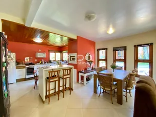 Ambiente interno de uma sala de estar com cozinha e sala de jantar em uma residência.