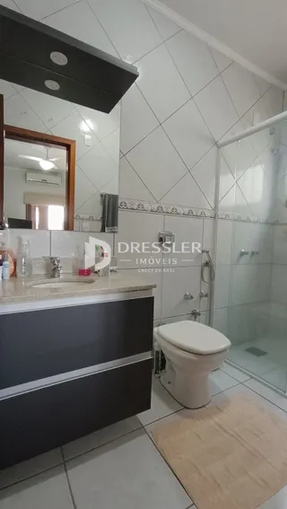 Foto de um banheiro com revestimento cerâmico e box de vidro.