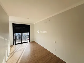 Interior de uma sala com piso de madeira e porta de vidro.