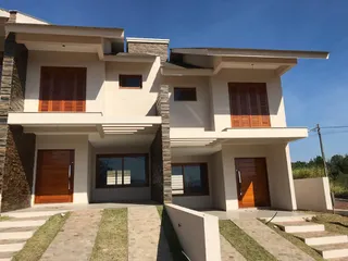 Fachada de uma casa moderna com revestimento claro e portas de madeira em Lajeado, Brasil.