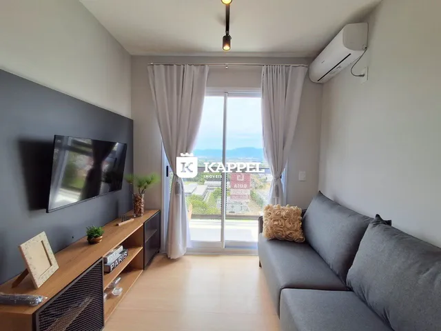 Sala de estar com sofá e televisão em um apartamento em Lajeado.