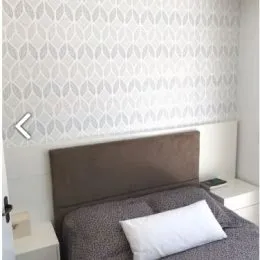 Foto de um quarto mostrando a cabeceira e a roupa de cama.