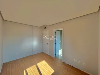 Interior de uma sala com piso de madeira clara e paredes brancas.