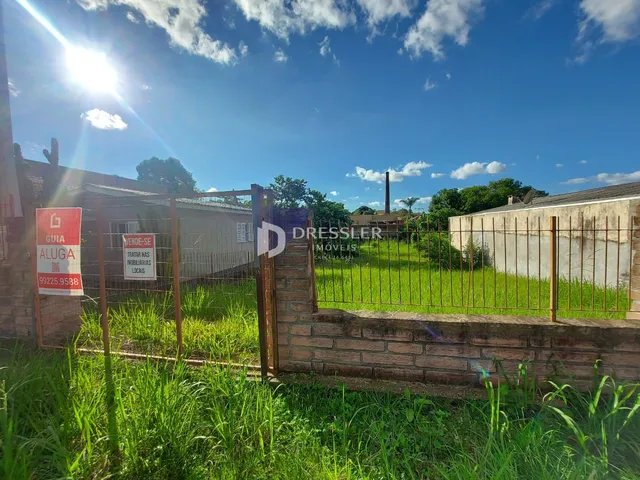 Vista externa da propriedade com cerca e vegetação alta.