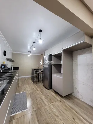 Cozinha moderna com armários brancos e piso de madeira clara.