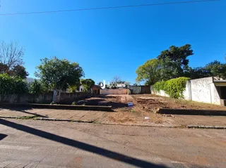 Vista externa de uma propriedade com muro e área de terra.
