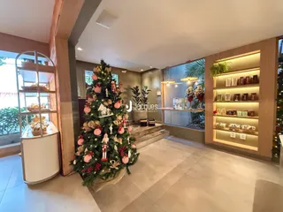 Ambiente interno de uma sala de estar com decoração natalina e estantes de madeira.