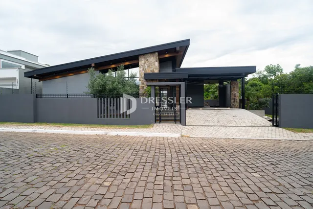Fachada moderna de uma residência em Lajeado, Brasil, com muro e área pavimentada.