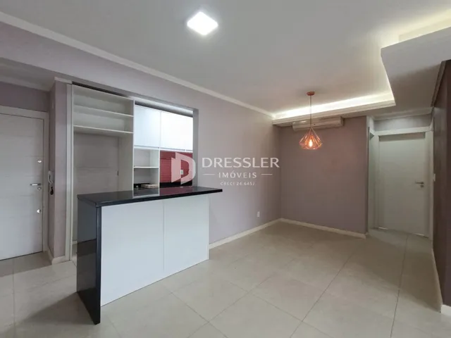 Ambiente interno de uma sala com revestimento claro e móveis brancos.
