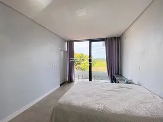 A foto mostra um quarto com paredes brancas e uma grande janela de vidro.